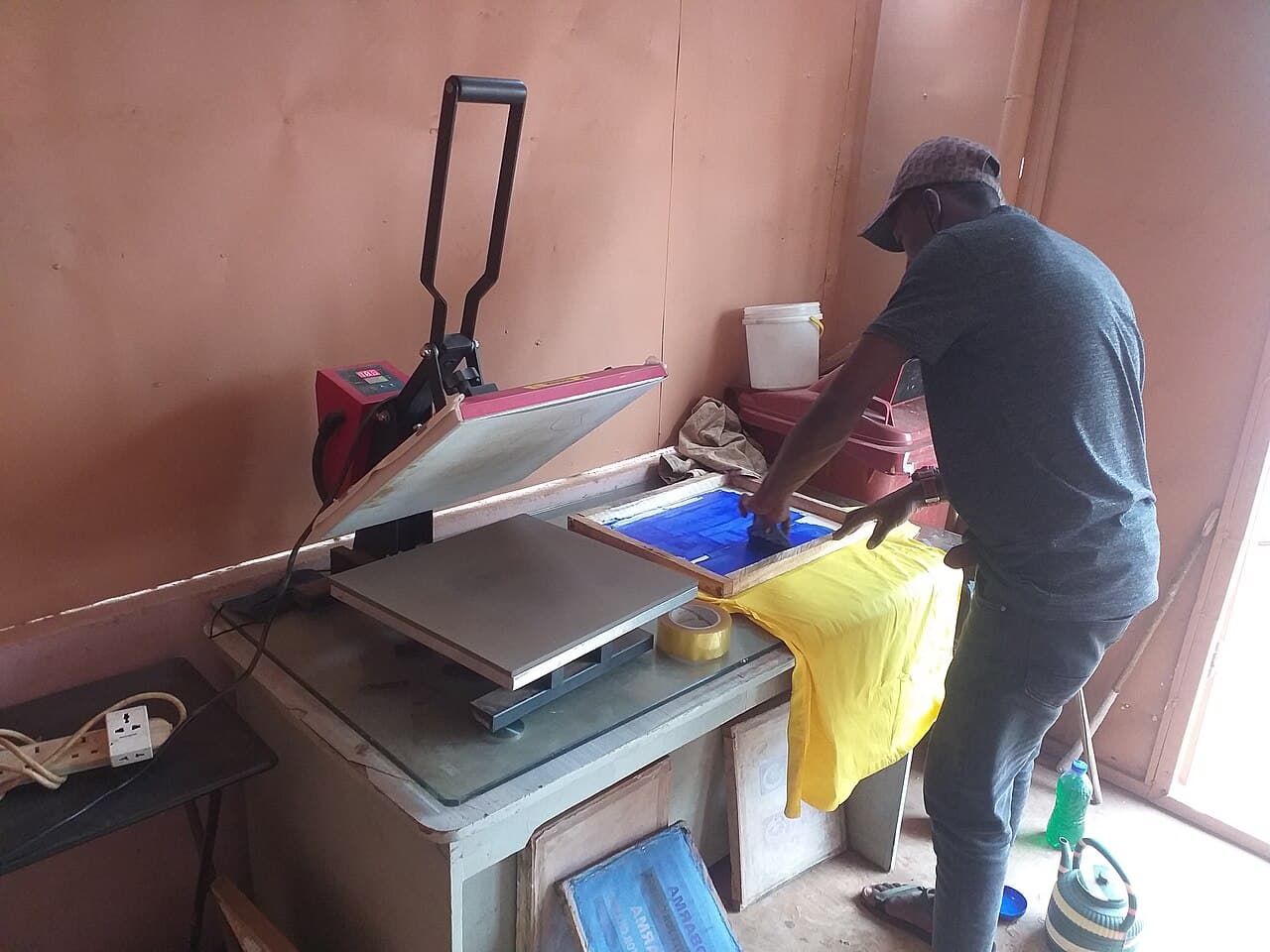 Profissional preparando uma camiseta em equipamento de estamparia, imagem ilustrativa